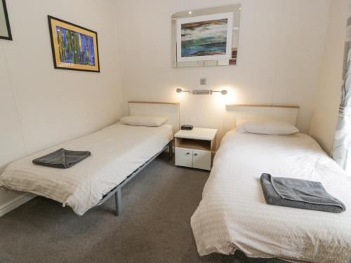 a room with two beds and a table and a mirror at Oyster Bay Lodge in Dalbeattie