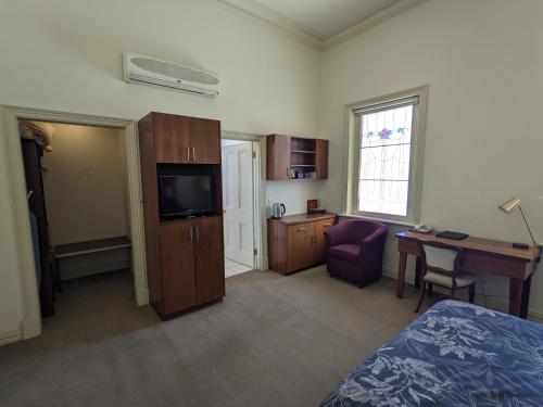 a hotel room with a bed and a desk and a television at The Astra Broken Hill in Broken Hill