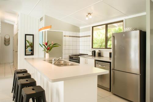 a kitchen with a stainless steel refrigerator and stools at B's Beach House on Muri Lagoon in Rarotonga