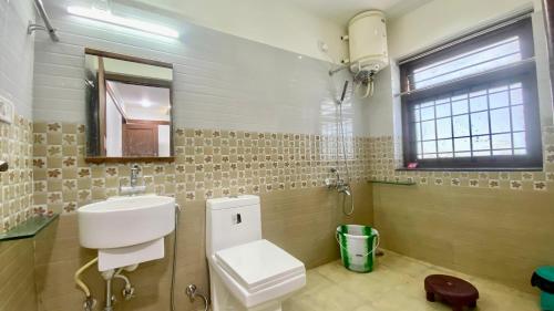 un bagno con lavandino, water e finestra di Willostays Alpine Mansion 6bhk a Kodaikānāl