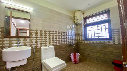 un bagno con lavandino, WC e specchio di Willostays Alpine Mansion 6bhk a Kodaikānāl
