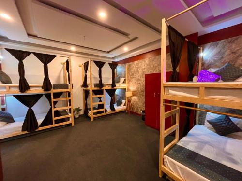 a room with three bunk beds with ties in them at VISTA HOSTEL Near Mall Road Manali - with Playing Zone & Gym in Manāli