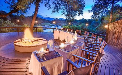 a row of tables and chairs on a deck with a fire pit at Karongwe - Kuname Safari Lodge in Hoedspruit