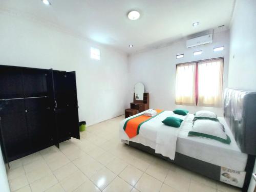 a large bedroom with a bed and a mirror at Homestay Jogja Samirono Dekat UNY by Simply Homy in Yogyakarta