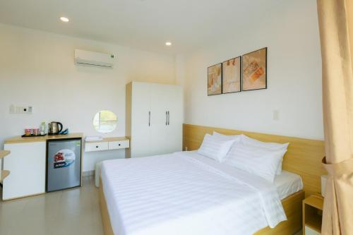 een slaapkamer met een wit bed en een kleine keuken bij BIG Hotel Sài Gòn in Ho Chi Minh-stad