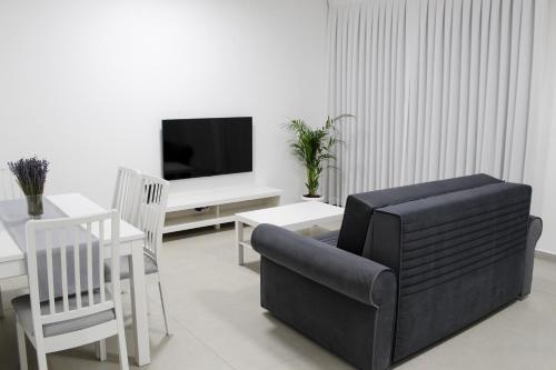 a living room with a couch and a table and a tv at Luxury Suite Apartment #45 By Hashdera Eilat in Eilat