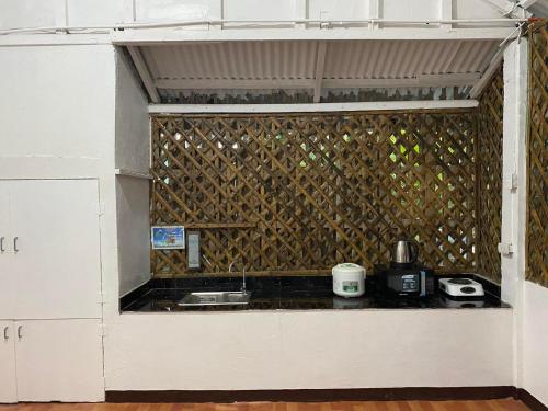 a kitchen with white cabinets and a wall with a counter at Ati Lodge Boracay in Boracay