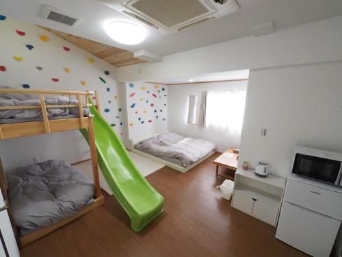 a room with two bunk beds and a green slide at locona +rakuta in Hyuga