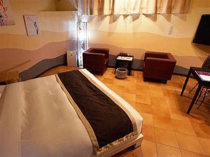 um quarto com uma cama e cadeiras num quarto em スパホテル　ティーズリゾート伊勢崎 em Nishi-kunisada