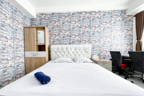 a bedroom with a white bed with a brick wall at Apartemen Riverview Cikarang by Room PDL 99 in Bekasi
