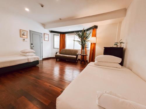 a room with two beds and a chair in it at Le Charme Vientiane Hotel in Vientiane