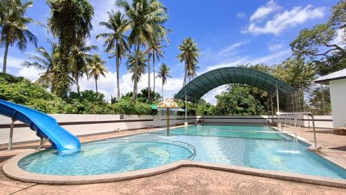 a swimming pool with a slide in a resort with palm trees at C Hotel in Jitra