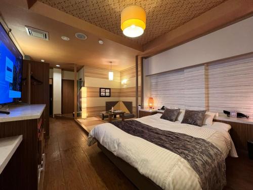 HOTEL SOLA chikugo MOTEL في Chikugo: غرفة نوم بسرير كبير وتلفزيون بشاشة مسطحة