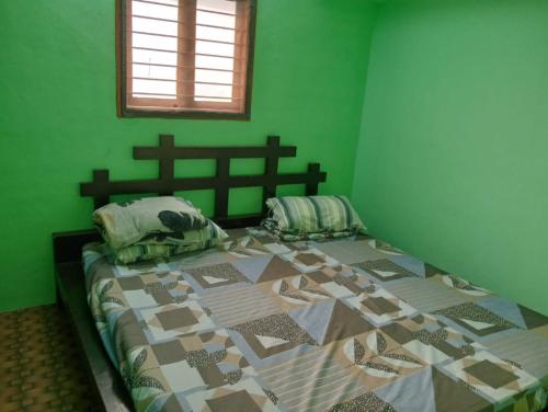 a bedroom with a bed with a green wall at KKA RESIDENCY in Coimbatore