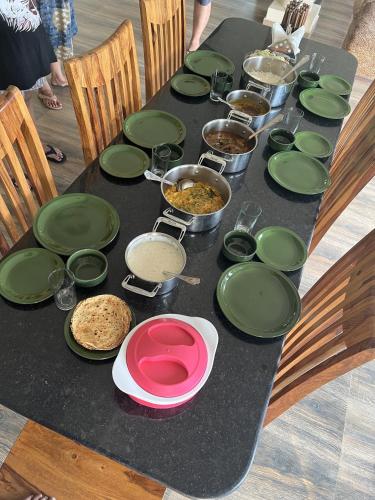 a table topped with green plates and bowls of food at Hideaway By Aahma in Rāmnagar
