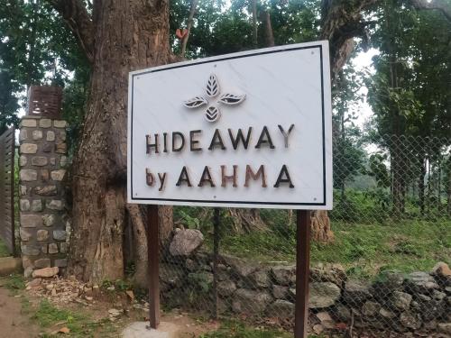 a sign for a hideaway by alkmaar in front of a tree at Hideaway By Aahma in Rāmnagar