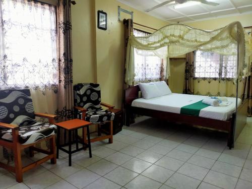 ein Schlafzimmer mit einem Bett und einem Stuhl darin in der Unterkunft Cs Apartment Mombasa Mtwapa in Mombasa
