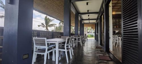 a dining room with white chairs and a table at Ikani Surf Resort in Pagudpud