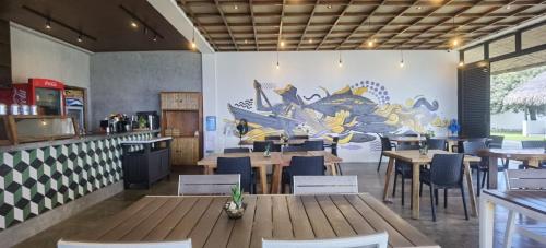 a restaurant with tables and chairs and a mural at Ikani Surf Resort in Pagudpud
