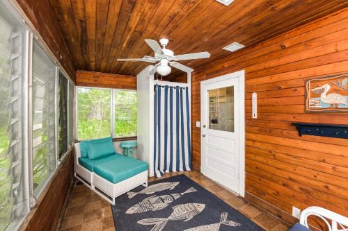 a porch with a ceiling fan and a green chair at Casa Posada - So Close You Can Hear the Waves Historic Beach Cottage w Beach Gear in Anna Maria