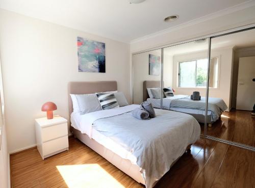 HallにあるCanberra Comfort Family Cottage with 5 Beds& Pet Welcomingのベッドルーム1室(ベッド2台、鏡付)