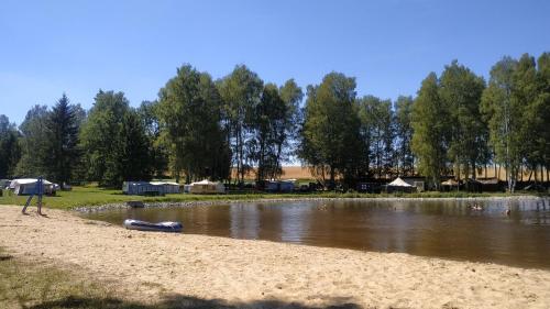 a lake with tents and a beach and trees at Autokemp Panistávka Žirovnice in Žirovnice