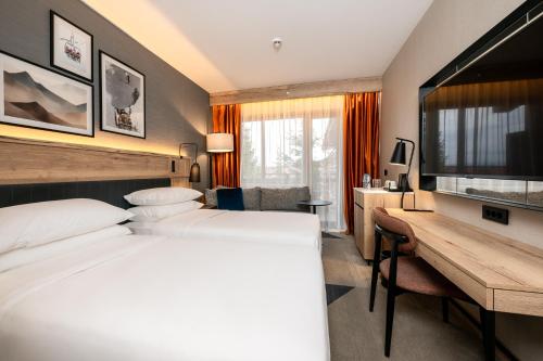 a hotel room with two beds and a desk at Four Points by Sheraton Bansko in Bansko