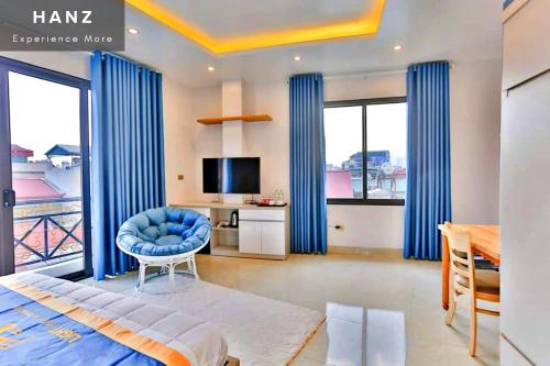 a bedroom with blue curtains and a bed and a television at HANZ Light House Hotel & Apartment in Hanoi