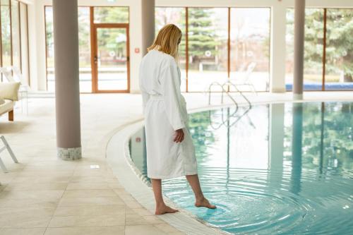 kobieta w białym szlafroku stojąca obok basenu w obiekcie Four Points by Sheraton Bansko w mieście Bansko