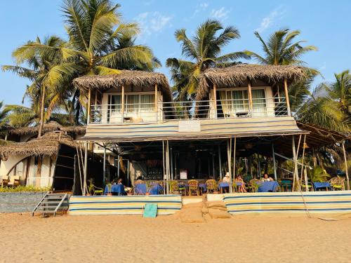 a resort on the beach with people sitting in chairs at Agonda Beach Chalets in Agonda
