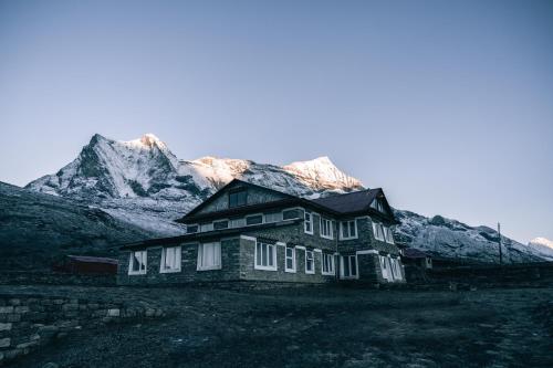 an old house with snow covered mountains in the background at Mountain Lodges of Nepal - Kongde in Kongde