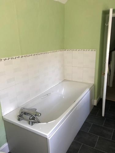 a white bath tub in a bathroom with green walls at No 37 in Bridport