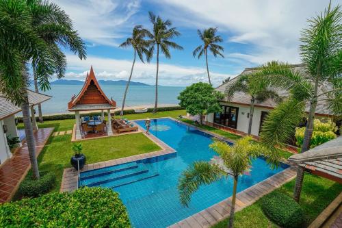 an aerial view of a resort pool with palm trees at Miskawaan Beachfront Villas in Mae Nam