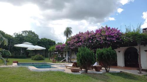uma casa com flores roxas e uma piscina em Kandire Posada Rural em San Ygnacio