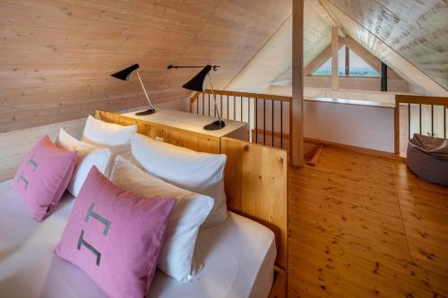 um quarto com uma cama com almofadas cor-de-rosa e brancas em Hainichhöfe Chalet 3 em Mülverstedt