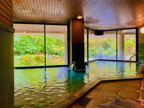a room with a pool of water with windows at Ryumontei Chiba Ryokan in Ōyu