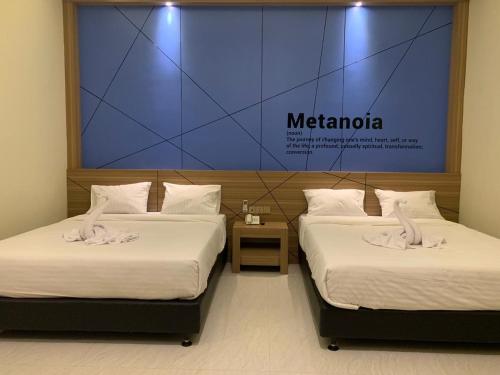 Bless Hotels في Sintang: سريرين في غرفة مع علامة تقرأ metaria