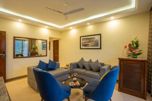 a living room with blue chairs and a couch at De Mandarin Beach Resort Suites & Villas, Candolim in Candolim