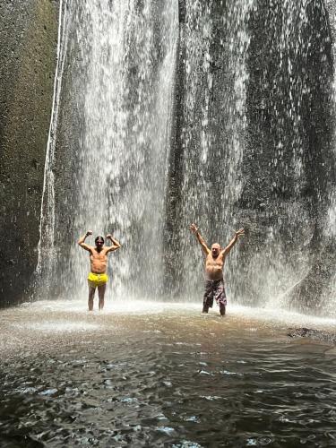 two people standing in the water in front of a waterfall at PINOKKIO B&B Restaurant in Jimbaran