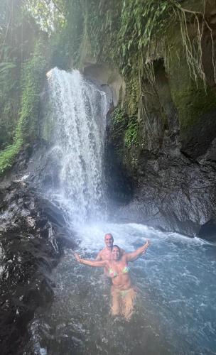 a man and woman standing in front of a waterfall at PINOKKIO B&B Restaurant in Jimbaran