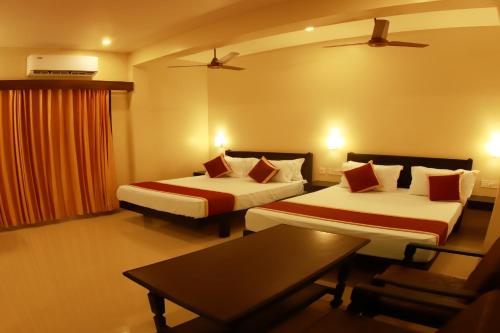 a hotel room with two beds and a table at Hotel Sri Devi in Kanyakumari