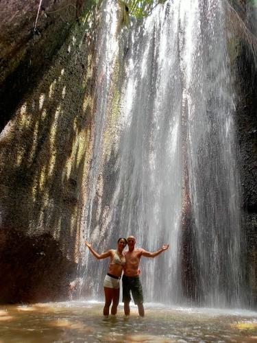 a man and woman standing in front of a waterfall at PINOKKIO B&B Restaurant in Jimbaran
