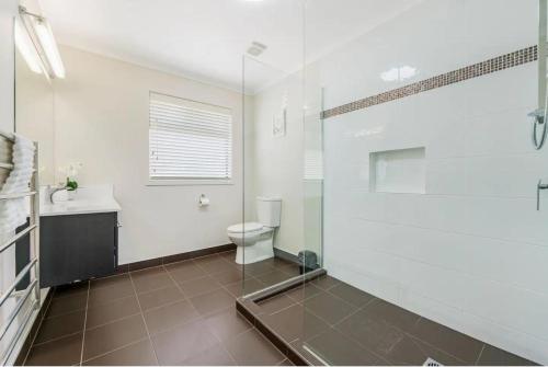 a bathroom with a shower and a toilet and a sink at Luxury Modern 3-BDR Oasis in Kumeu