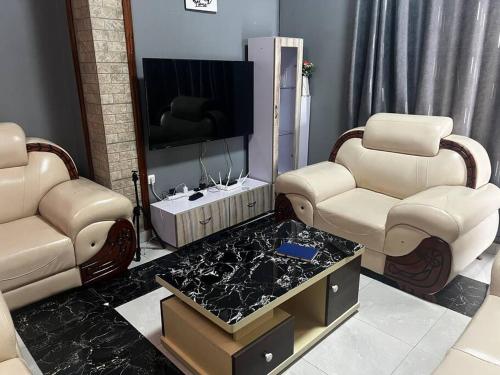 uma sala de estar com 2 cadeiras e uma televisão de ecrã plano em 2 bedroom apartment in Musanze( Benji) em Ruhengeri
