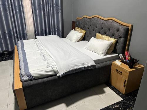 uma cama com uma cabeceira preta e lençóis e almofadas brancos em 2 bedroom apartment in Musanze( Benji) em Ruhengeri