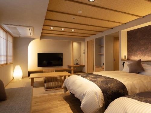 a hotel room with two beds and a flat screen tv at Hotel Kazurabashi in Miyoshi