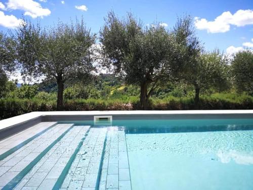 een zwembad met bomen op de achtergrond bij Appartamento nel castello del cardaneto in Montone