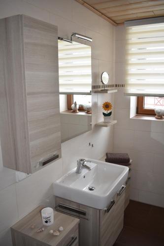 - une salle de bains blanche avec lavabo et 2 fenêtres dans l'établissement Gästehaus Siebert, à Bad Brambach