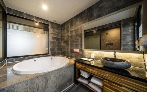 a bathroom with a large tub and a sink at Kkaebi Stay in Pohang
