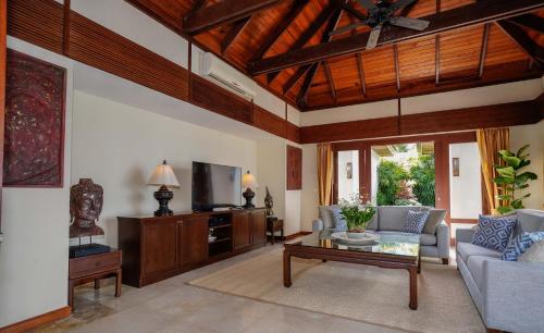a living room with a couch and a tv at Miskawaan Beachfront Villas in Mae Nam